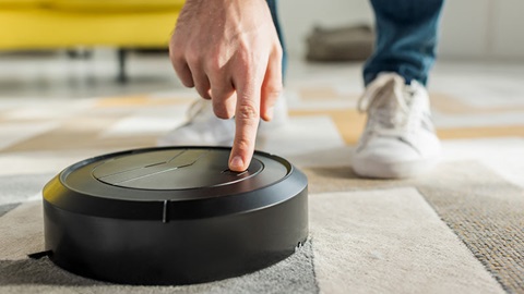 homme fait démarrer son aspirateur robot